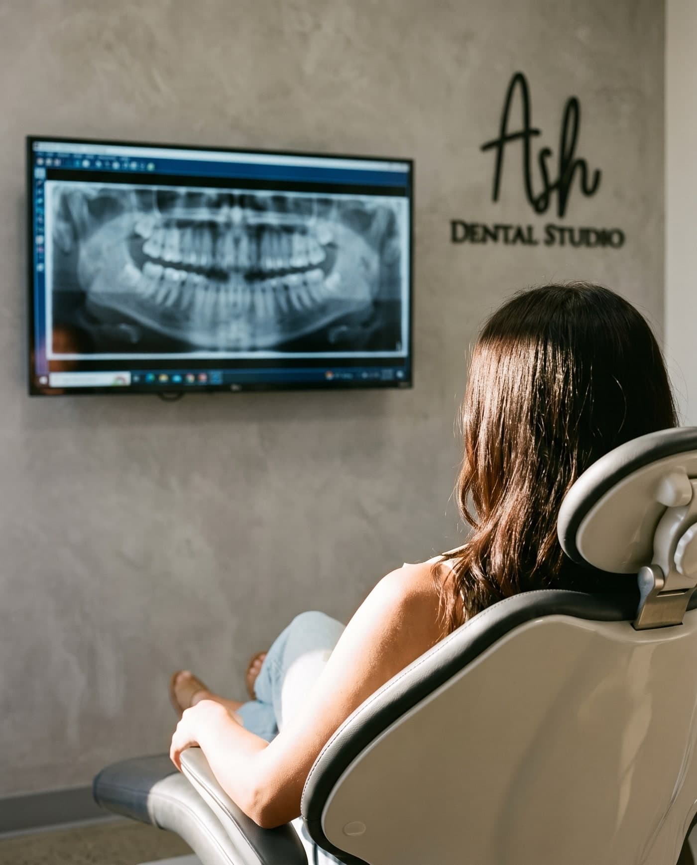 A patient in the chair looking at her dental X-ray on screen